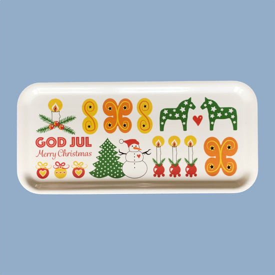 Tablett weß mit Illustrationen in gelb, grün, Orange und rot. Links steht GOD JUL in roten Großbuchstaben, darunter Merry Christmas in rot. Es sind Lussekatter ein Schneemann, Dalapferde und Kugelleuchter abgebildet